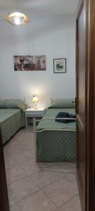 um quarto com 2 camas e uma mesa com um candeeiro em Villetta vacanze em Torpè