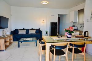 a kitchen and living room with a table and a blue couch at Domus Vita Heraklio in Néa Alikarnassós