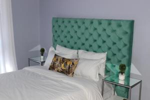 a bedroom with a large bed with a green padded headboard at Blue Agave MH in Lusaka