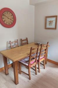 einen Holztisch mit Stühlen und eine Uhr an der Wand in der Unterkunft Upper Deck in Eyemouth