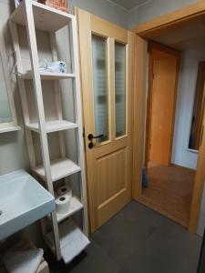 a bathroom with a sink and a door with shelves at Siesta apartment Bled in Bled