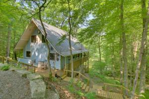 a blue house in the middle of the forest at Charming and Secluded Riverside Cabin and 3 Decks in North Vernon
