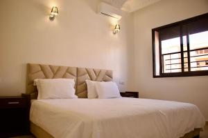 sypialnia z łóżkiem z białą pościelą i oknem w obiekcie Magnifique appartement Marrakech w Marakeszu