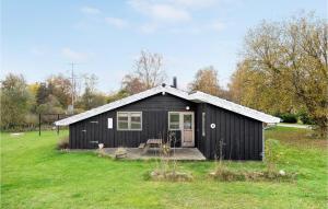 a black house in a field with a grass yard at Gorgeous Home In Askeby With Sauna in Askeby