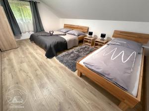 sypialnia z 2 łóżkami i drewnianą podłogą w obiekcie Welness chata pod Sitnom w Bańskiej Szczawnicy