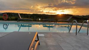 a swimming pool with a sunset in the background at Agriturismo con cucina Il Favaio in Paciano