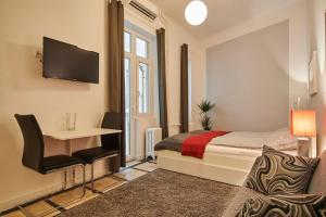 Super Central Studio Apartment - with balcony في بودابست: غرفة نوم بسرير ومكتب وتلفزيون