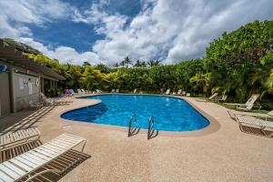 a swimming pool with lounge chairs and trees at Ekolu 1403 in Wailea