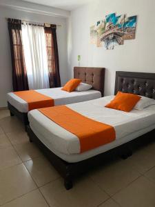 Dos camas en una habitación de hotel con naranja y blanco en Hotel Gran Palacio, en Pereira