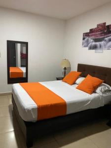 1 dormitorio con 1 cama con almohadas de color naranja y espejo en Hotel Gran Palacio, en Pereira