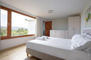 a bedroom with a large white bed with a large window at Eliva house in Chania