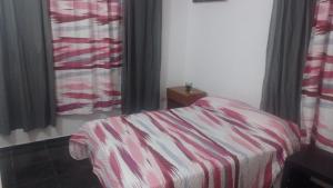 een slaapkamer met een bed met een gestreepte deken bij departamento de arriba temporal in Formosa