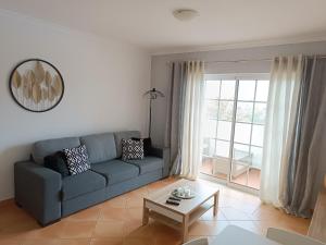 uma sala de estar com um sofá azul e uma mesa em Mar à Vista Algarve Summer em Portimão