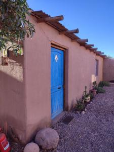 una puerta azul en el lateral de una casa en Cabañas Rica-Rica Lodge, en San Pedro de Atacama