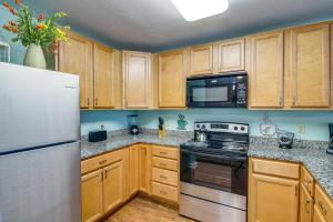 a kitchen with wooden cabinets and stainless steel appliances at Pigeon Forge Condo with Community Amenities! in Pigeon Forge