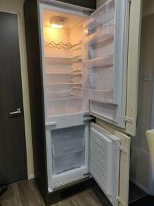 an empty refrigerator with its door open in a kitchen at Calm & Cosy (sleeps up to 6) - Oakdene Forest Park in Ferndown
