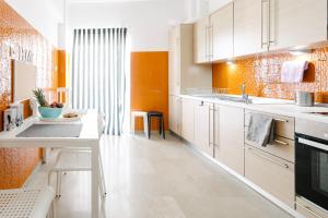 una cocina con armarios blancos y una pared de color naranja en Acropolis view apartment in Athens, en Atenas
