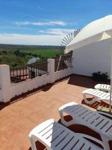 - Balcón con sillas blancas y sombrilla en Lonja del Ribacillo, Casa Rural en Almodóvar del Río