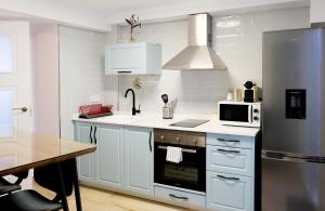 a kitchen with white cabinets and a stainless steel refrigerator at Lonja del Ribacillo, Casa Rural in Almodóvar del Río