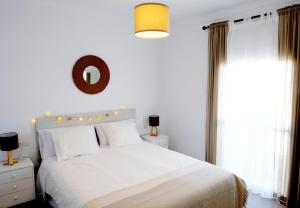 a bedroom with a white bed and a mirror at Lonja del Ribacillo, Casa Rural in Almodóvar del Río