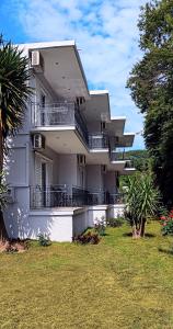 a large white house with balconies and a yard at Petros Studios Valtos in Parga