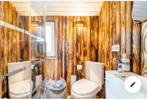 un bagno con un water e un lavandino di Roulotte du puits avec jacuzzi et sauna privatif a Havinnes