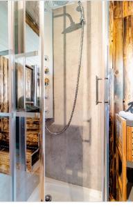 W łazience z przeszklonymi drzwiami znajduje się prysznic. w obiekcie Roulotte du puits avec jacuzzi et sauna privatif 