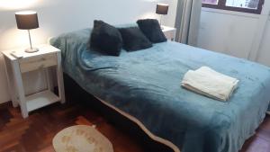 Schlafzimmer mit einem Bett mit blauer Bettwäsche und Kissen in der Unterkunft 9y45 in La Plata