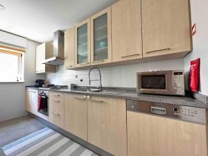 a kitchen with wooden cabinets and a microwave at Canidelo Modern Apartment in Vila Nova de Gaia