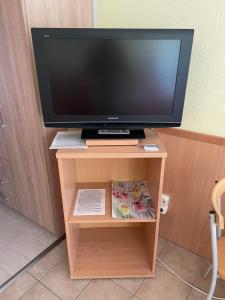 telewizor z płaskim ekranem na drewnianym stojaku telewizyjnym w obiekcie Jókai Apartmanok w Balatonfüred