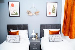 two beds in a bedroom with orange curtains at TD-Stourb DUDLEY 3 Bed House-PERFECT FOR CONTRACTORS-FAMILIES-LONG & SHORT STAY in Woodside