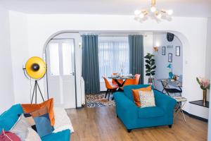 TD Stourb Dudley - Luxurious 3 Bedroom House - Sleeps 7 - DY1 - Long Stay for Contractors & Families في Woodside: غرفة معيشة مع أريكة زرقاء وغرفة طعام