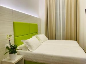 a bedroom with a white bed with a green headboard at Hotel Fioralba in Milan