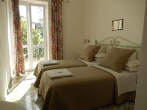 two beds in a room with a window at Hotel Europa in Ischia