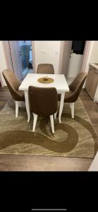 una mesa de comedor blanca y sillas sobre una alfombra en Glamur Apartman - Ulcinj, en Ulcinj
