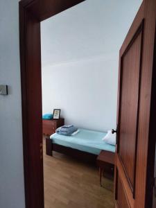 a small bedroom with a bed and a wooden door at Casa sossegada na Batalha in Batalha