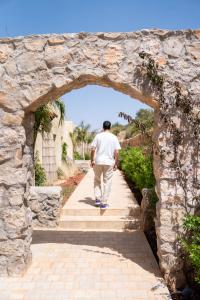 un homme qui marche à travers une voûte en pierre dans l'établissement Dar El Mandar - Ferme & Table d'Hôte Berbère, à Bhalil