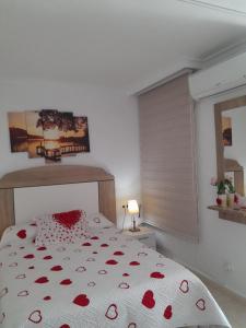 a white bedroom with a bed with red flowers on it at Estudio La Corbeta in Torrox Costa