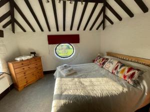 a bedroom with a bed and a round window at The Coach House in Holywell