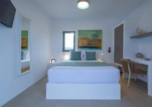 a white bedroom with a bed and a desk at Korfi de Milo in Adamas