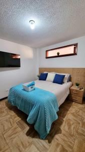 a bedroom with a bed with a blue blanket on it at Hermosos apartamentos en Funza in Funza