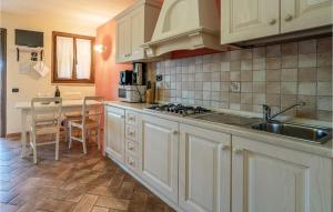 - une cuisine avec des placards blancs, un évier et une table dans l'établissement Nice Home In San Giovanni With Kitchen, à Montefiore dellʼAso