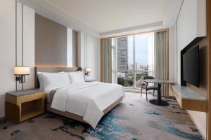 a bedroom with a large bed and a large window at The Westin Manila in Manila