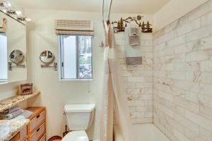 a white bathroom with a shower and a toilet at Cozy Forest Falls Rental Cabin Near Hiking Trails! in Forest Falls +17 photos