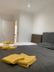 - une chambre avec un lit et 2 serviettes jaunes dans l'établissement Luxury Flat Near Greenwich Park, à Londres