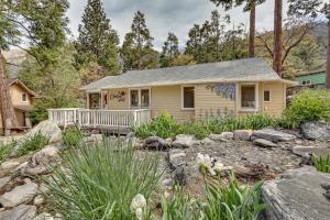 a small yellow house with a porch in a garden at Cozy Forest Falls Rental Cabin Near Hiking Trails! in Forest Falls