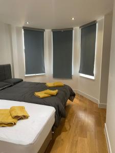 two beds in a room with windows with blue blinds at Luxury Flat Near Greenwich Park in London