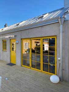 un bâtiment avec des portes jaunes et de nombreuses fenêtres dans l'établissement Casa Annie & Nadja - Toppmodernt centralt i Borgholm, à Borgholm