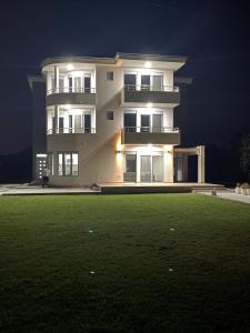 a large white building at night with a green lawn at Hamptons Village Apartments Ada Bojana in Ulcinj