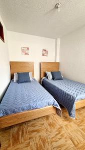 two beds in a room with wooden floors at Hermosos apartamentos en Funza in Funza